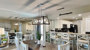 Een moderne keuken met witte kastjes, een houten eettafel en een hanglamp.