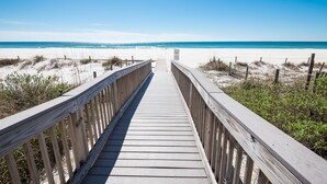 Een houten looppad naar een strand, met heldere luchten.