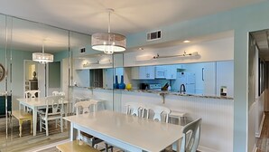 Een moderne keuken met witte kasten, een centraal eiland en hanglampen.
