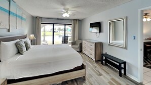 Un dormitorio con una cama grande, ventilador de techo, televisor y vista a un campo de golf por la ventana.