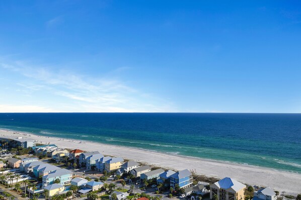A coastal resort with beachfront properties, clear skies, and a view of the ocean.