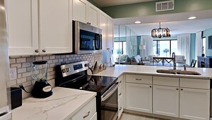 A modern kitchen with white cabinets, a built-in microwave, a blender, and a stove. - Edgewater Villa #3315 | Beach, Golf, & 11 Pools! (Panama City Beach)