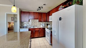 Une cuisine moderne avec des meubles en bois, un réfrigérateur blanc et un pare-feu en carreaux.