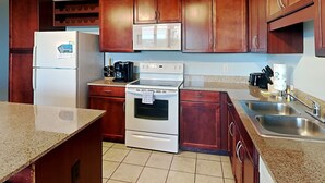 A kitchen with wooden cabinets, a refrigerator, a microwave, an oven, and a sink. - Laketown Wharf #1337 | Waterfront Paradise! (Panama City Beach)