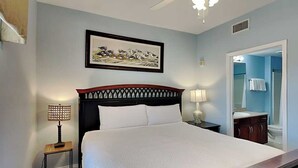 A bedroom with a bed, a nightstand, a lamp, a ceiling fan, and a framed picture on the wall. - Laketown Wharf #1337 | Waterfront Paradise! (Panama City Beach)