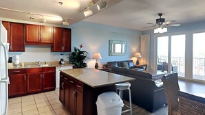 A modern kitchen with wooden cabinets, a central island, and a dining area with wicker furniture. - Laketown Wharf #1337 | Waterfront Paradise! (Panama City Beach)