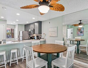 A modern kitchen with grey cabinets, stainless steel appliances, and a wooden island with seating.