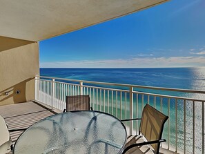 Enjoy the ocean view from this balcony with a glass table and two chairs.