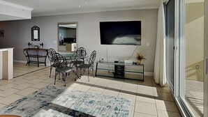 Un salon moderne comprenant un coin repas, un ventilateur de plafond, un téléviseur à écran plat et une porte-fenêtre coulissante.
