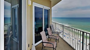 A balcony with a view of the beach, featuring a table and chairs. - Grandview East #1305 | Breathtaking views! (Panama City Beach)