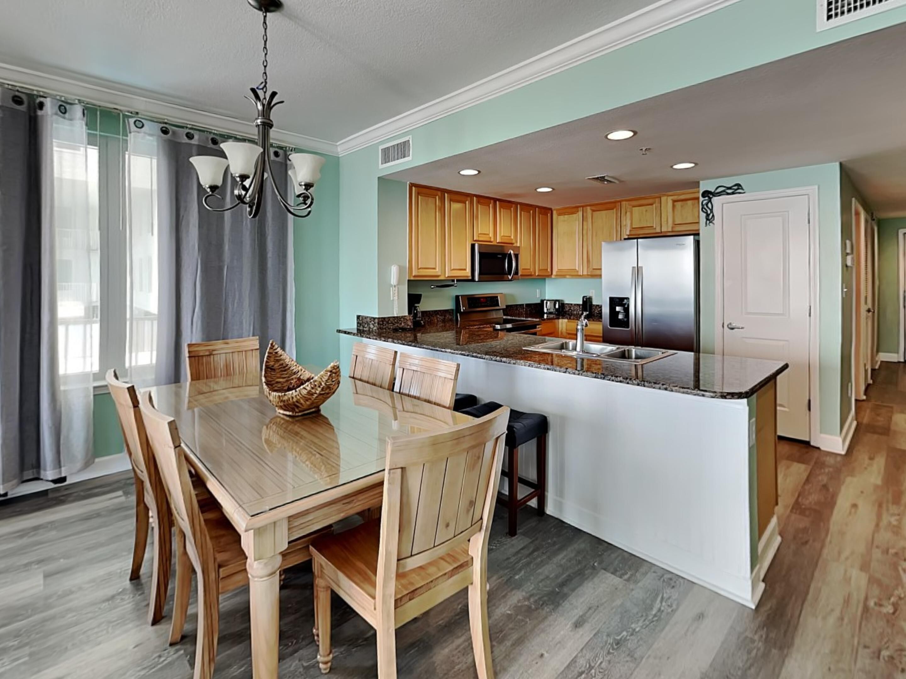 A modern kitchen with wooden cabinets, a stainless steel refrigerator, and a central island.