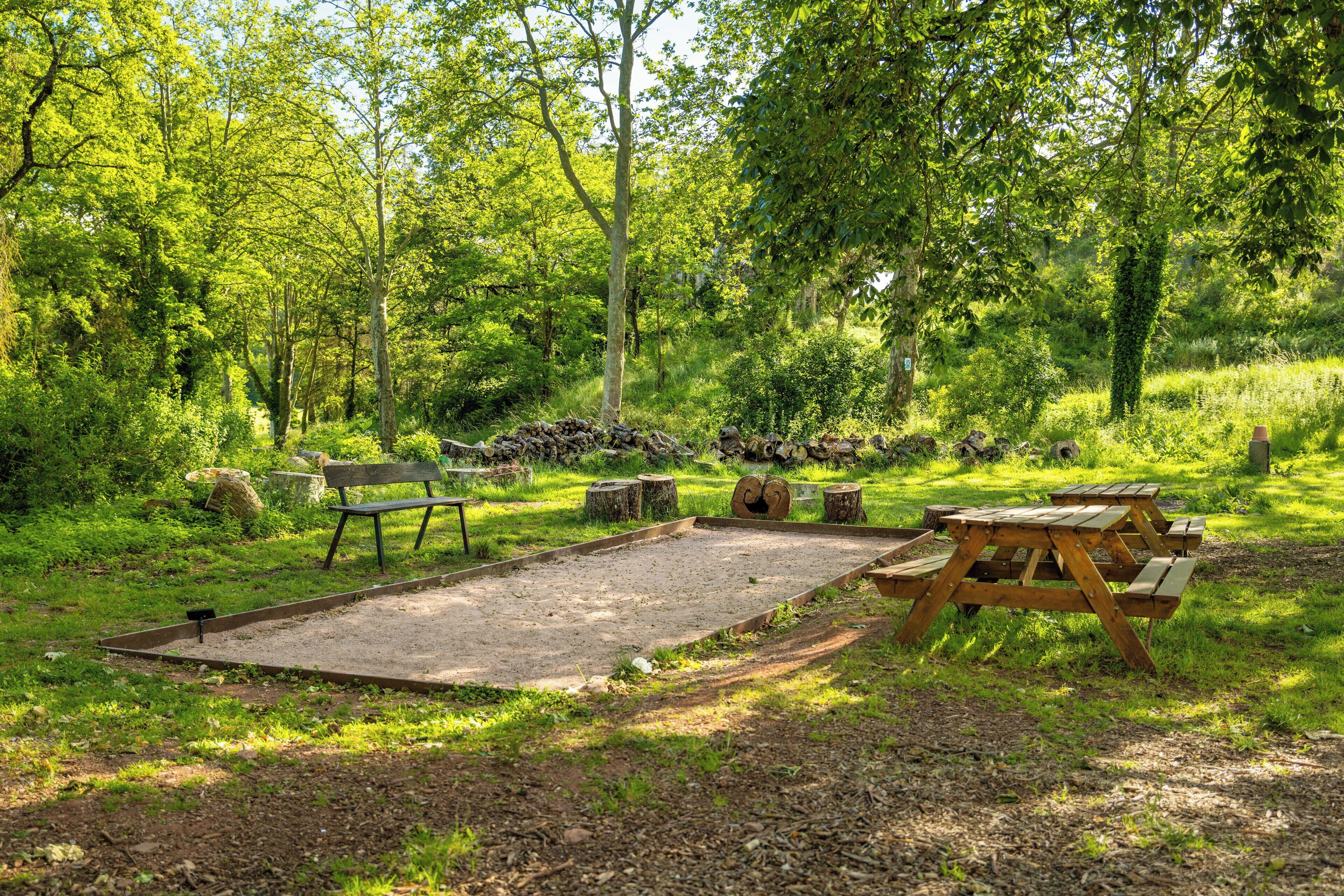 A picnic area with benches and a table in a wooded setting.