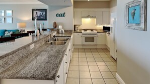 Eine moderne Küche mit einer Granit-Arbeitsplatte, einem Edelstahl-Spülbecken und weißen Schränken.