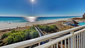 Blick auf den Strand vom Balkon mit Pool und Sonnenschirmen.