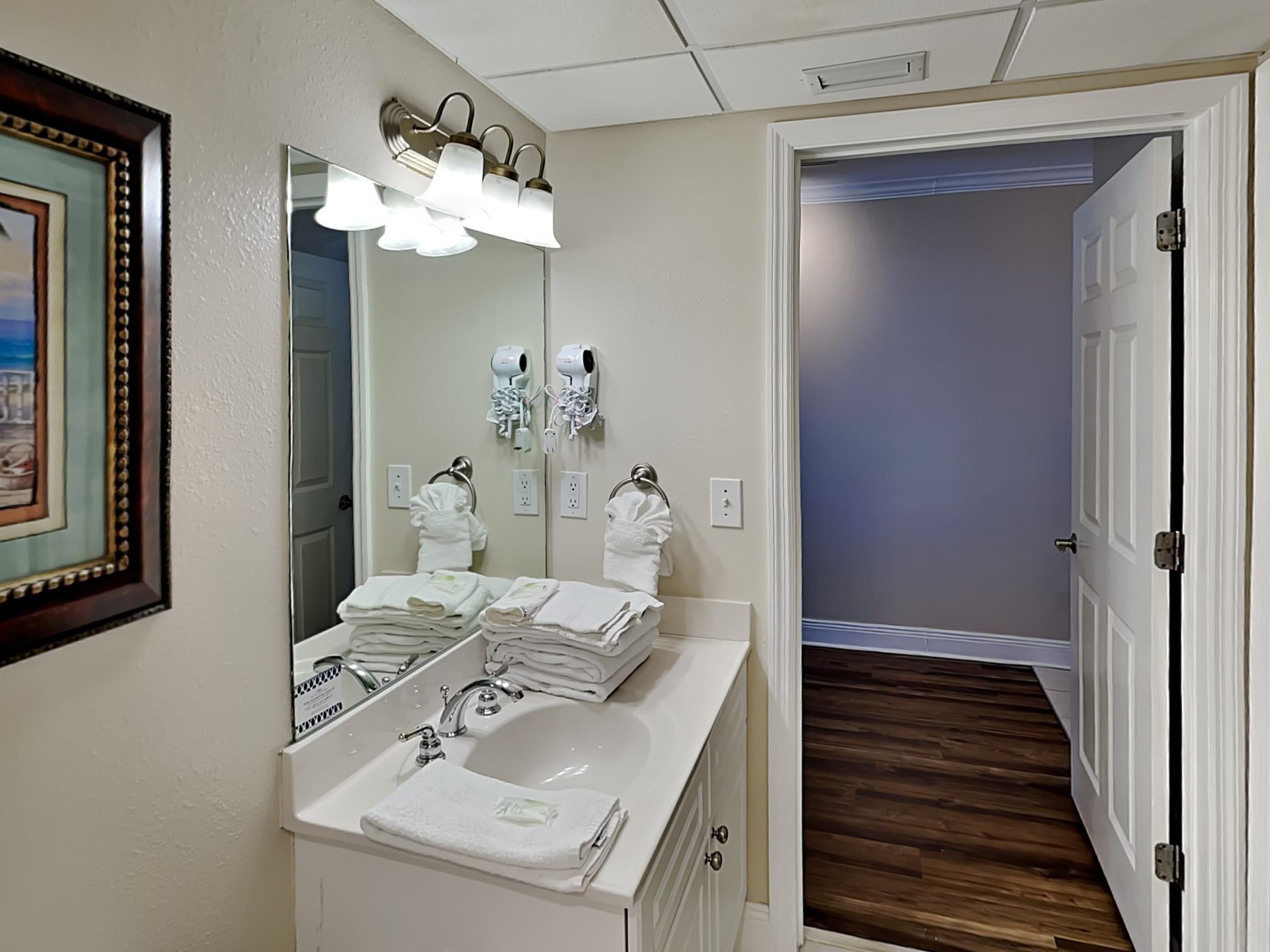 A bathroom with a white sink, a mirror, and a towel rack with folded towels.