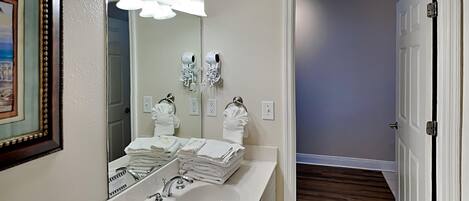 A bathroom with a white sink, a mirror, and a towel rack with folded towels.