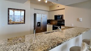 A modern kitchen with granite countertops, stainless steel appliances, and white cabinetry.