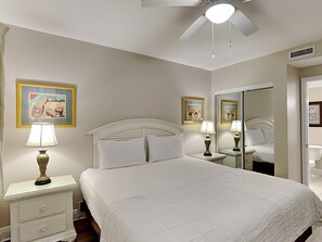 A hotel room with a bed, nightstands, lamps, a ceiling fan, and artwork on the walls. - Emerald Beach #335 | 3 Pools, Gym, Dining! (Panama City Beach)