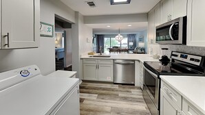 Una cocina moderna con armarios blancos, electrodomésticos de acero inoxidable y una isla central.