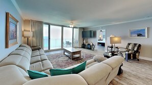 Ein geräumiges Wohnzimmer mit einer großen Couch, einem Couchtisch und einem Fernseher.