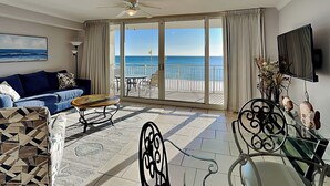 A spacious living room with a large sliding glass door leading to a balcony with a view of the ocean. - Emerald Beach #328 | Views, Pool, Dining! (Panama City Beach)