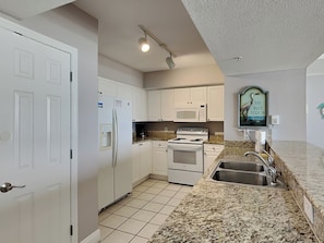 Kitchen features a stainless steel sink, microwave, and granite countertop.