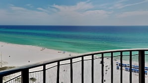 A beach view from a balcony with a railing, clear sky, and calm sea. - Watercrest #1401 | Warm turquoise waters! (Panama City Beach)