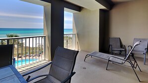 A balcony with two lounge chairs and a pool view.