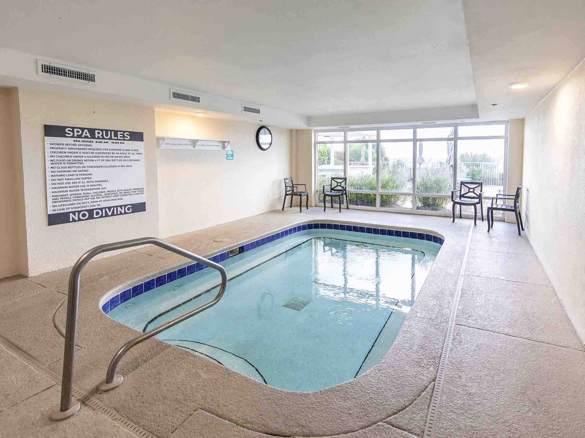 Un espace piscine agrémenté d’un panneau indiquant les règles du spa et d’un avertissement interdisant de plonger.