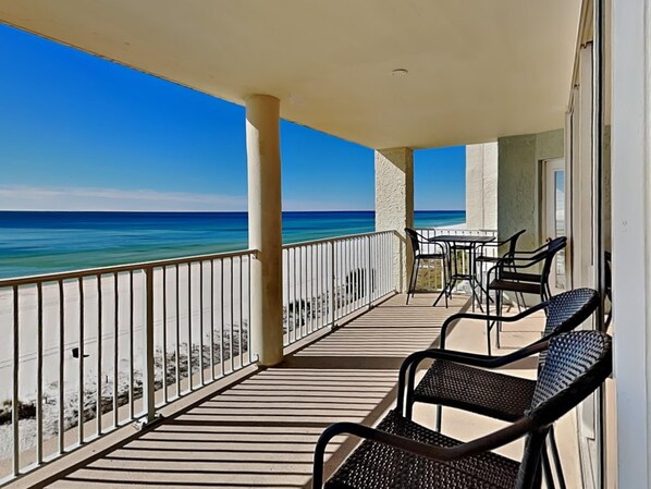 Een balkon met uitzicht op de oceaan, met een tafel en stoelen.