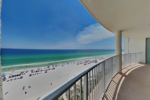 Un balcon donnant sur une plage, avec une balustrade et un ciel dégagé.