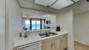Una cocina moderna con lavavajillas, doble pileta y vista al océano a través del ventanal.