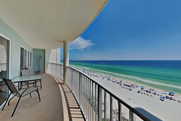 Un balcon avec vue sur la plage, une table et des chaises.