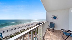 Ein Balkon mit Blick auf den Strand, ein Stuhl und eine Sonnen-Dekoration an der Wand.