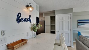 A modern kitchen with a marble countertop, a wooden sideboard, and a wall-mounted light fixture.