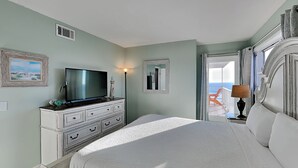 A bedroom with a bed, a dresser, a television, a lamp, and a view of the ocean. - Summit Beach Resort #901 | Gorgeous Views! (Panama City Beach)