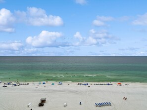 Une plage avec des tentes et des parasols, un ciel dégagé et l’océan.