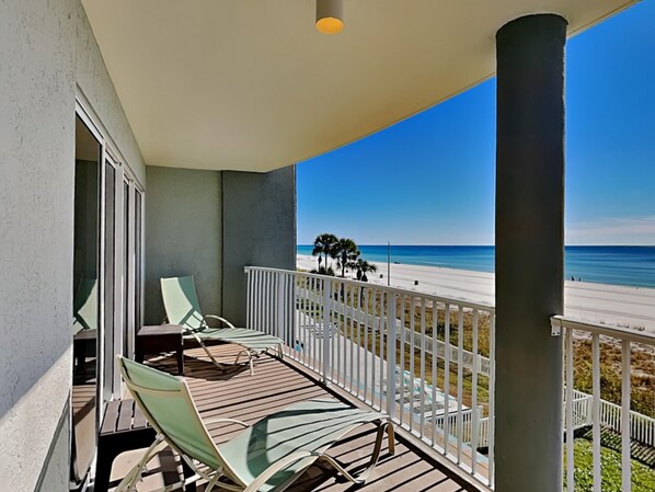 Ein Balkon mit Blick auf einen Strand, ausgestattet mit Geländer und wenigen Stühlen.