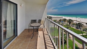 A balcony with a table and chairs, overlooking a beach with clear skies. - Summit Beach Resort #526 | Gorgeous Views! (Panama City Beach)