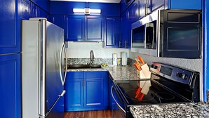 A kitchen with blue cabinets, stainless steel appliances, and a granite countertop. - Summit Beach Resort #430 | Gorgeous Views! (Panama City Beach)