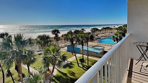 A balcony with a view of a beach, a pool, and palm trees. - Summit Beach Resort #429 | Gorgeous Views! (Panama City Beach)