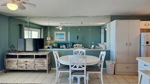 Cocina compacta con comedor, armarios blancos y ventilador de techo.