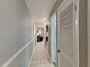 Stylish hallway leads to a cozy bedroom with a bed and nightstand.