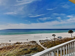 Blick auf einen Strand, bewölkter Himmel, feiner Sand und etwas Vegetation.