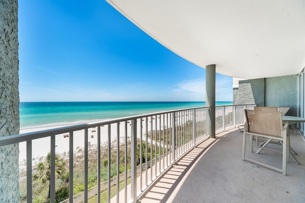 A balcony with a view of the beach and ocean.