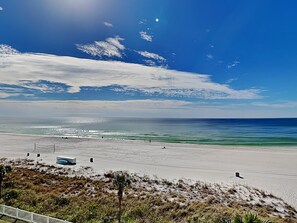 Ein Strand mit blauem Himmel, ruhiger See und einigen Spaziergängern.