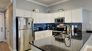 Una cocina moderna con armarios blancos, electrodomésticos de acero inoxidable y una encimera de granito negro.