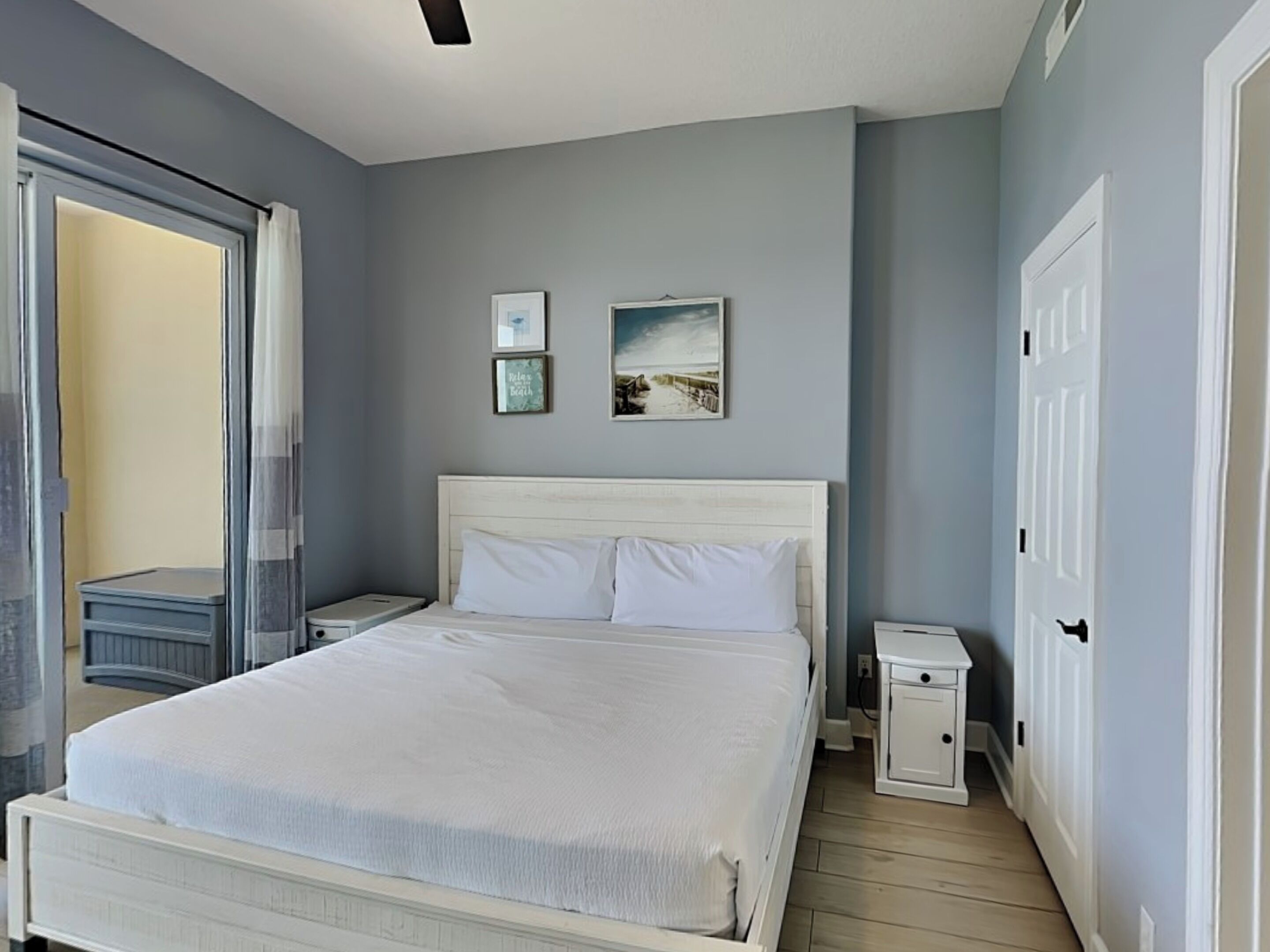 Een slaapkamer met een groot bed, een nachtkastje en een deur.