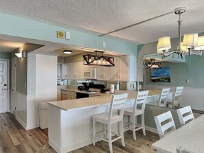 Enjoy meals in the kitchen with a central island and dining area featuring a long table and chandelier.