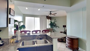 A kitchen with granite countertops, a built-in sink, and a ceiling fan. - Shores of Panama #1510 | Lagoon Pool! (Panama City Beach)